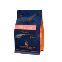 A bag of Four Sisters espresso coffee beans with notes of chocolate ganache, caramel, and key lime from Copper Door Coffee Roasters.