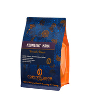 A bag of Copper Door Coffee Roaster's Midnight Mama coffee beans with tasting notes of tobacco, dark chocolate, and walnut